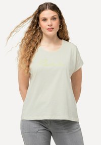 Camiseta corta de manga en verde claro con un texto en cursiva amarillo que dice "love" en el frente. Tela suave con un ajuste relajado.