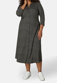 Mustapaitainen napillinen mekko, jossa on kolme neljäsosaa hihat ja rento leikkaus, yhdistettynä valkoisiin lenkkareihin. Pehmeä, kevyt kangas.