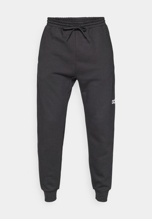 Pantalones de chándal negros, hechos de una suave mezcla de algodón, con una cinturilla elástica con cordón y un pequeño logo blanco en el lado izquierdo.