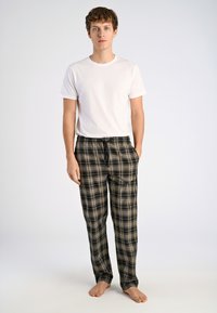 Witte korte mouwen t-shirt voor heren, gecombineerd met zwart en beige geblokte loungebroeken met een elastische tailleband en zijzakken.