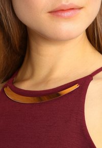 Bordowy top bez rękawów o subtelnej teksturze, z złotym metalicznym akcentem wzdłuż dekoltu. Prosty fason, bez wzorów.