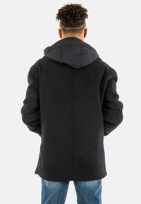 Abrigo de mezcla de lana negra con capucha negra acolchada, que presenta un corte recto, mangas largas y detalles en la parte trasera sin costuras.