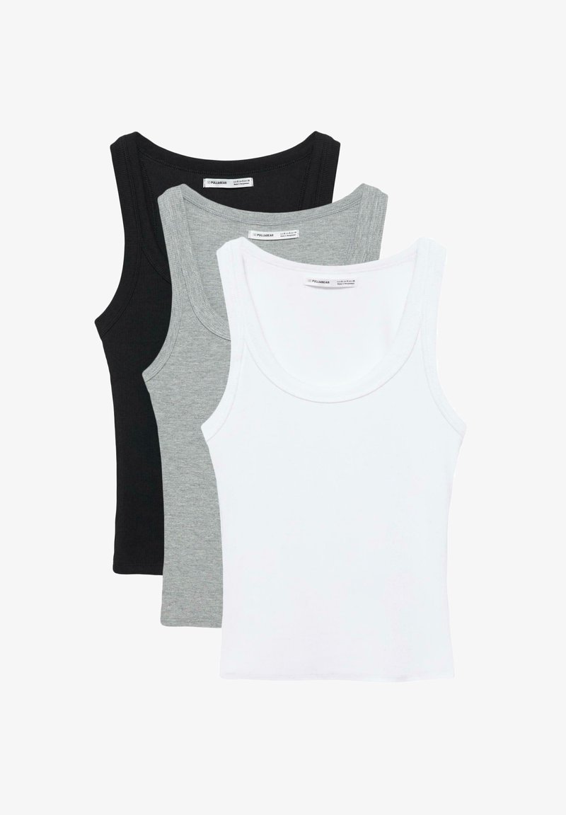 Drei ärmellose, gerippte Tanktops in Weiß, Hellgrau und Schwarz, übereinandergelegt mit Weiß oben, Draufsicht.