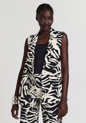 Gilet senza maniche in tessuto con stampa zebra bianco e nero, dotato di colletto a rever, bottoni frontali e tasche laterali, abbinato a pantaloni coordinati.