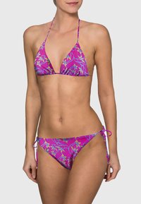 Bikini triangle en rose vibrant avec un motif floral. Doté de liens ajustables en haut et en bas. Tissu lisse et extensible.