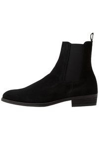 Svart mocka Chelsea-stövle med elastiska sidopaneler, rund tå, låg klack och en dragflik baktill för enkel påtagning.