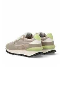 Zapatillas con una parte superior en un beige neutro, materiales de ante y malla, detalles en blanco y verde suave, y una gruesa suela de goma negra.