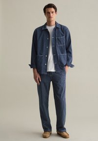 Blue striped button-up jacket and matching pants in a relaxed fit. The fabric features a textured weave, with visible stitching accents.