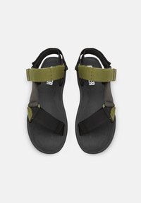Sandalias negras y verde oliva con correas ajustables, suelas de goma gruesas y una plantilla texturizada para mayor agarre. Diseño minimalista.