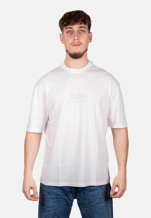 T-shirt bianco in cotone con maniche corte, colletto rotondo, caratterizzato da un logo in rilievo sottile di colore rosa. Il modello indossa jeans in denim blu.
