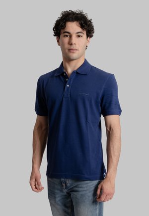 Polo shirt blu navy in materiale cotone con colletto classico, maniche corte e patta con tre bottoni; presenta una piccola etichetta con logo.