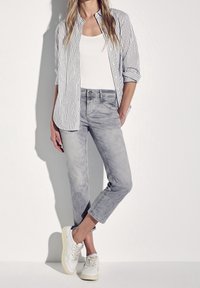 Lightweight, gray denim pants with a slim fit and rolled cuffs, paired with a white tank top and a striped button-down shirt. White sneakers.