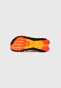 Semelle d'une chaussure avec un design en caoutchouc noir, orange et jaune, dotée de grips texturés et d'un motif de semelle multidirectionnel.