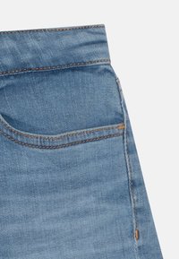 Světle modré džíny z denimu s přední kapsou, podrobným švem v kontrastní barvě a hladkou texturou.