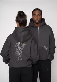 Grauer Zip-up-Hoodie aus weichem Stoff, mit künstlerischer Stickerei von Blumen- und Figurenmotiven auf der Rückseite und der Vorderseite des Taschenbereichs.
