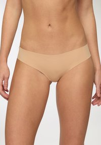 Intimo bikini beige con design liscio e senza cuciture. Presenta un'ampia cintura morbida e un taglio a copertura minima. Tessuto morbido al tatto.