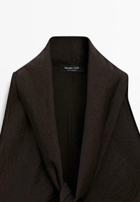 Schwarzes Oberbekleidungsstück mit weitem Kragen, aus strukturiertem Stoff und mit einem eingenähten Markenetikett. Keine sichtbaren Verschlüsse oder Knöpfe.