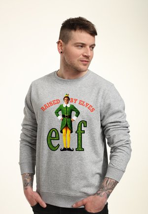Gray sweatshirt featuring a colorful graphic of an elf in green attire, with orange text "RAISED BY ELVES" and the word "elf" in green letters.