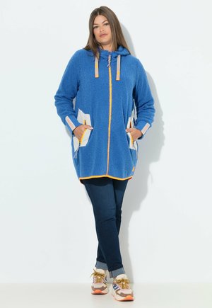 Blauwe fleece hoodiejack met een ritssluiting aan de voorkant, oranje accentafwerking, twee voorzakken en lichtgrijze paneeldetails aan de zijkanten.