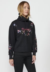 Hoodie noir avec une texture en chevrons, ornée d'une broderie florale colorée et d'un col à cordon. Poignets et ourlet côtelés.