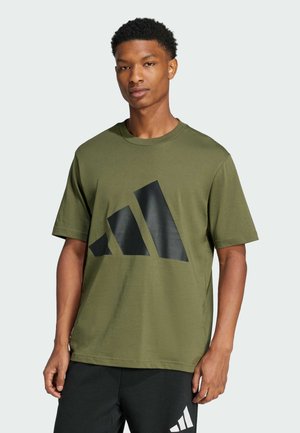 T-shirt z bawełny w kolorze oliwkowym z dużym czarnym logo graficznym z przodu. Krótkie rękawy, okrągły dekolt i luźny krój.