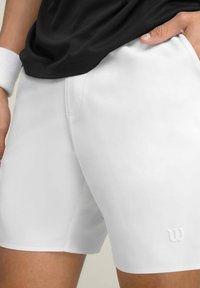 Pantalones cortos deportivos blancos hechos de una tela suave y ligera. Presenta un pequeño logo en relieve en la parte inferior izquierda.