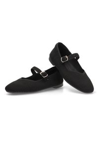 Zapatos Mary Jane negros con un tejido ribeteado texturizado, suela plana y una pequeña correa con hebilla en el empeine.