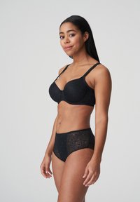 Sostén negro de encaje con copas moldeadas y tirantes ajustables, combinado con pantalones cortos negros de cintura alta con una superposición de encaje.