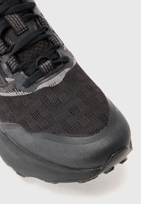 Black athletic shoe with a textured mesh upper, reinforced toe cap, and contrasting light grey accents on the eyelet and tongue.