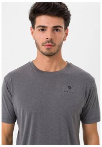 Grå t-shirt med korte ærmer lavet af tekstureret stof, der har et lille logo på venstre side. Enkel, rund halsringning og afslappet pasform.