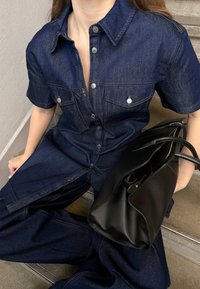 Tume sinine teksatooted, lühikeste varrukatega, rinnataskudega, hõbedaste nööpidega ja kontrastsete õmblustega; kombineeritud musta nahast käekotiga.