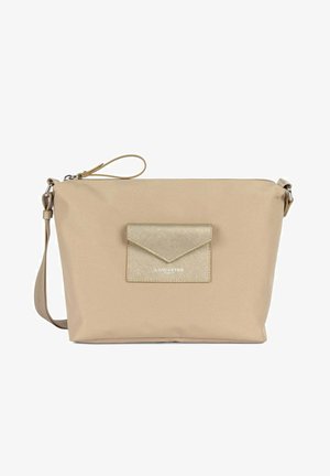 Sac bandoulière en nylon beige avec une poche plate à l'avant, des accents métalliques, une bandoulière ajustable et une fermeture éclair. Présente des détails de logo sur la poche.