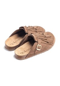 Bruine suède instapschoenen met franjes, een gouden gespsluiting en een geprofileerde zool. De binnenkant heeft een voetbed van natuurlijke vezels.