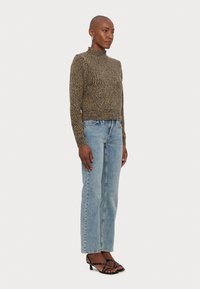 Pull court en tricot avec des paillettes dorées et noires, associé à un jean droit bleu clair et des sandales à talons noires à lanières.