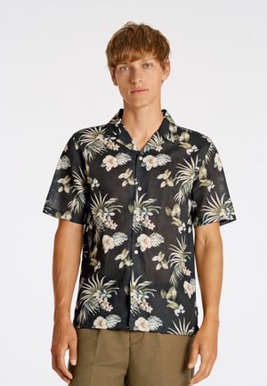 Chemise noire à manches courtes ornée d'un motif floral tropical avec des feuilles vertes et des fleurs de couleur claire. Fabriquée en tissu léger.