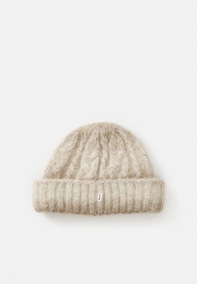 Beige strikket ulllue med brettet ribbekant og lite hvitt merke merket "NN.07" på en hvit bakgrunn.
