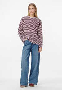 Duggičast, bordo i bijeli prugasti top s okruglim izrezom, u kombinaciji s visokim, širokim plavim trapericama i bordo obućom.