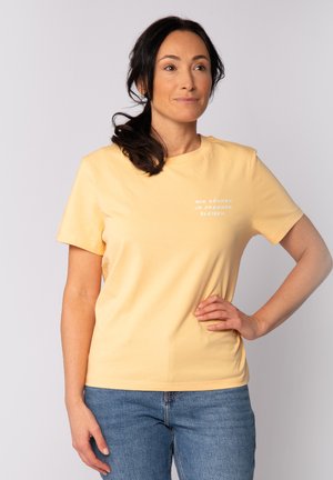 T-shirt jaune à manches courtes en coton, avec un col ras du cou et un design en texte blanc sur la poitrine. Coupe classique avec une texture lisse.
