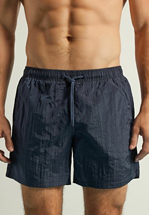 Dunkelblaue Badehose aus leichtem, strukturiertem Stoff. Verfügt über einen elastischen Bund mit Kordelzug und einem lässigen Schnitt.