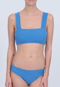 Ensemble de bikini bleu comprenant un haut à encolure carrée avec de larges bretelles et un bas taille basse assorti, fabriqué dans un tissu doux, au design à couvrance minimale.