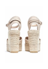 Sandales compensées en suède beige avec une sangle de cheville adjustable et une plateforme en jute texturé, dotées d'un haut talon carré.