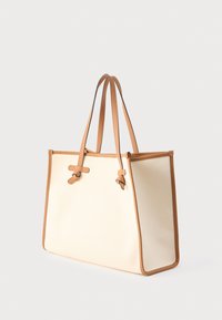 Borsa tote in tela beige con dettagli e manici in pelle color cuoio. Presenta una forma rettangolare, due manici e fondo piatto per stabilità.