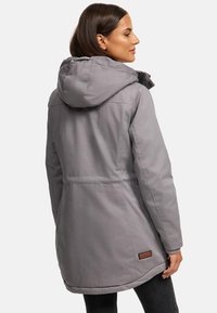 Gray insulated jacket with a hood, featuring a drawstring, side pockets, and a leather tag at the bottom. Smooth, textured fabric.