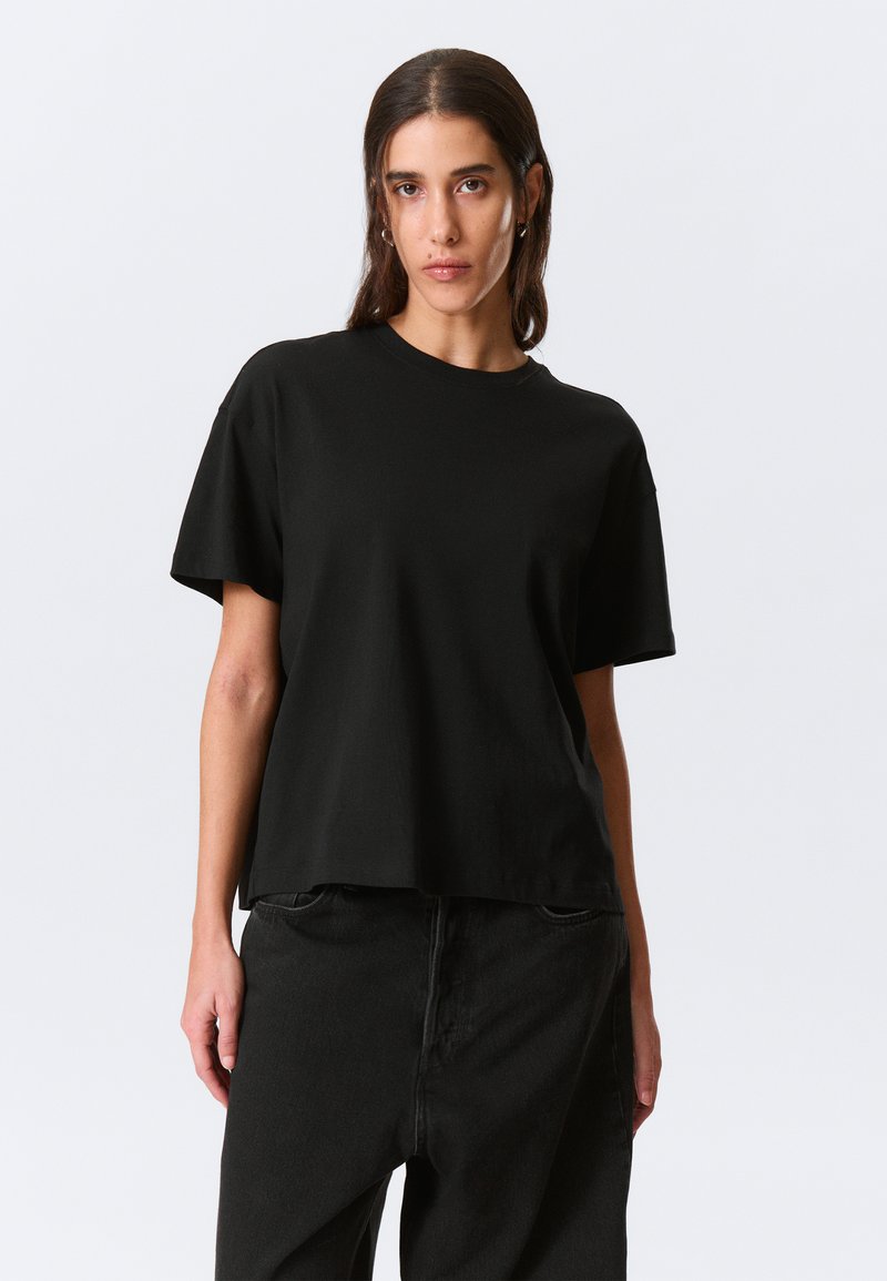 Black cotton t-shirt featuring a round neckline and short sleeves, with a relaxed fit and minimalistic design. No patterns or embellishments.