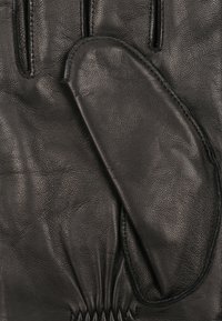 Sort læderhandske med en separat tommelfinger og en vante-stil sektion til fingrene, prydet med rynkede detaljer ved håndleddet.