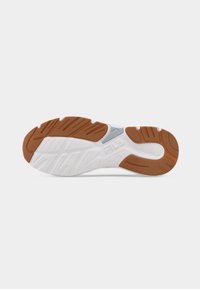 Η σόλα ενός αθλητικού παπουτσιού με λευκή βάση και καστανές λαστιχένιες επιφάνειες πρόσφυσης, με το λογότυπο FILA χαραγμένο στο κέντρο.