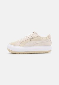 Sneaker en suède beige avec semelle en caoutchouc blanche et beige. Présente un logo PUMA, une texture lisse et un design à bout arrondi.