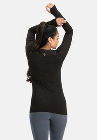 Schwarzes Langarmshirt mit Daumenlöchern, tailliertem Schnitt und dezentem Logo auf der Rückseite. Weiches, elastisches Material, ideal zum Layering.
