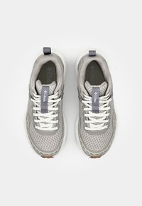 Světle šedé tenisky s vrškem z prodyšné síťoviny, bílými tkaničkami a fialovými detaily. Mají polstrovanou mezipodešev a poutko na patě pro snadné nazouvání.