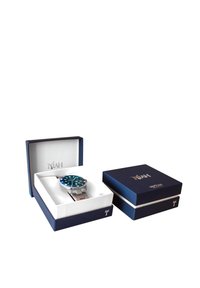 Montre-bracelet argentée avec un cadran teal, un bracelet en acier inoxydable et un boîtier rond, présentée dans une boîte de présentation bleue. Deux boîtes sont visibles.